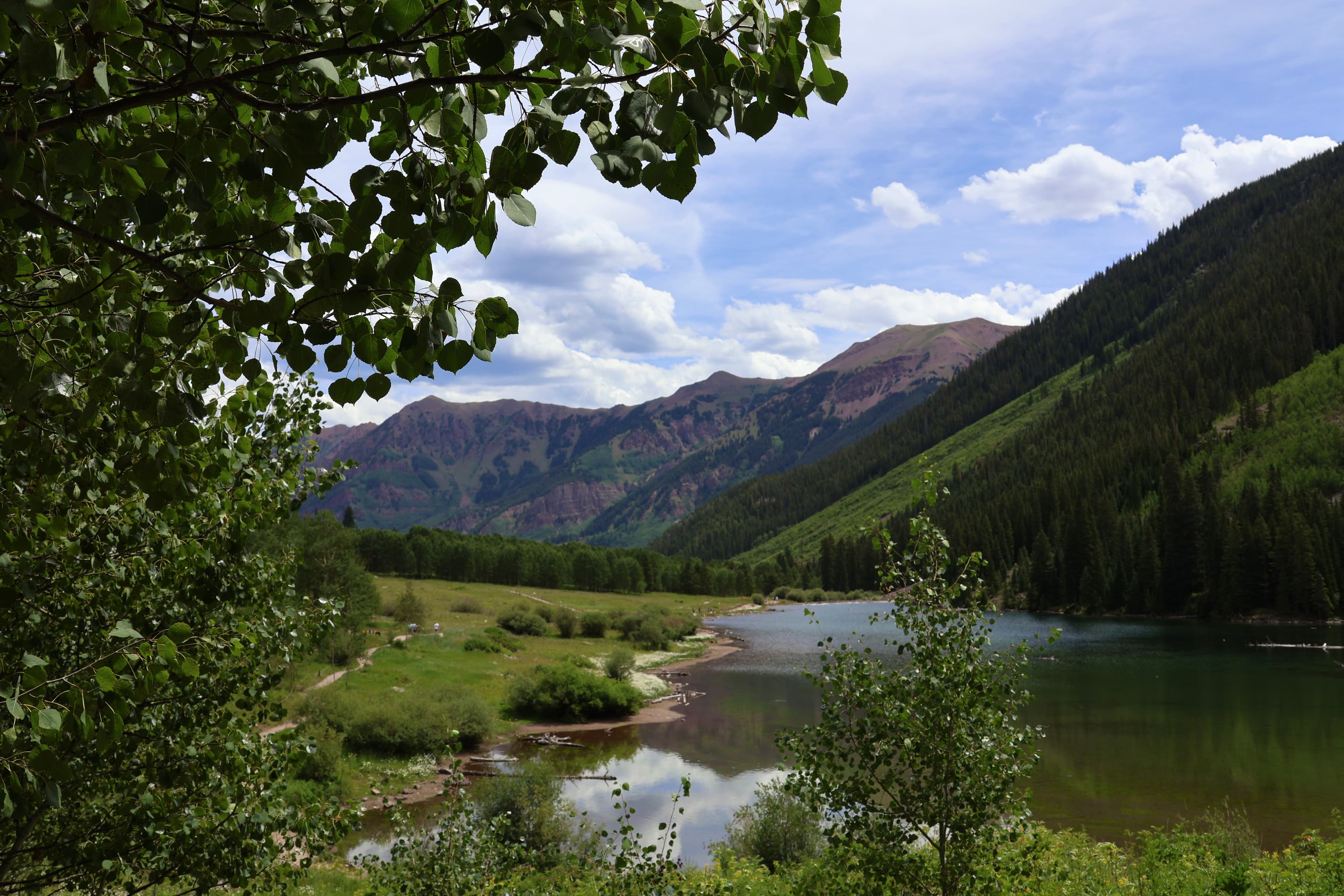 Mountain lake surrounded by forest and hills under a blue sky